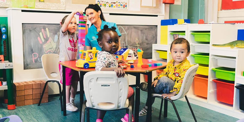 Children and a practitioner playing together at a table