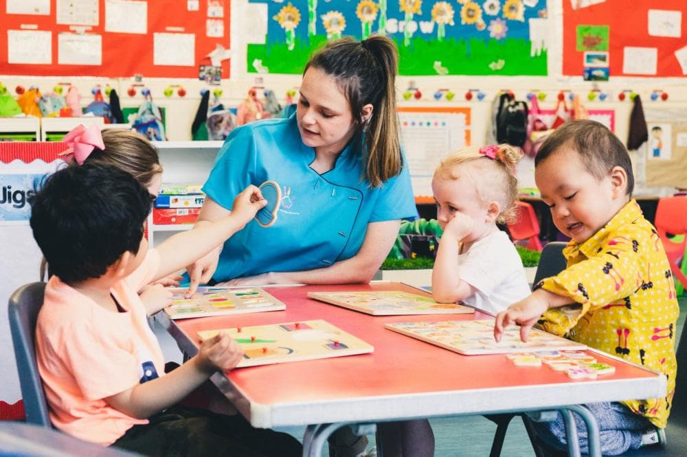 Nursery practitioner supporting children with an activity